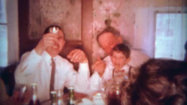 1963: Italian family eating spaghetti pasta dinner at packed kitchen table. BUFFALO, NEW YORK