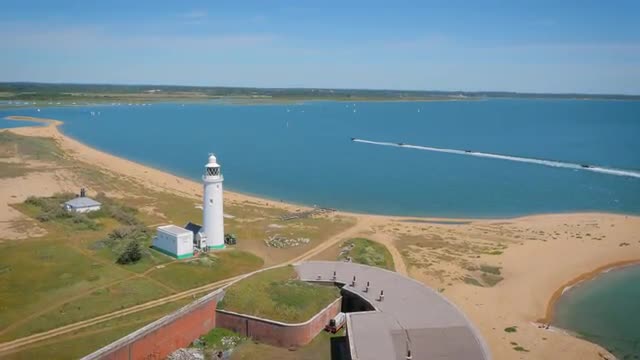 Aerial film of Rib boats in convoy passing lighthouse