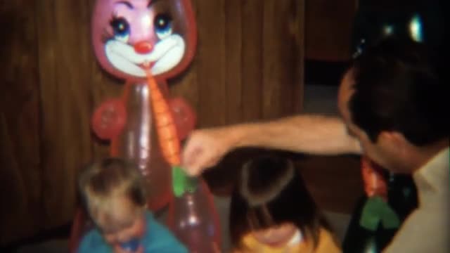 1974: Grandpa plays with blow up Easter bunny dolls and kids.