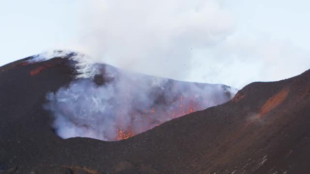 Lava erupting from volcano during the day