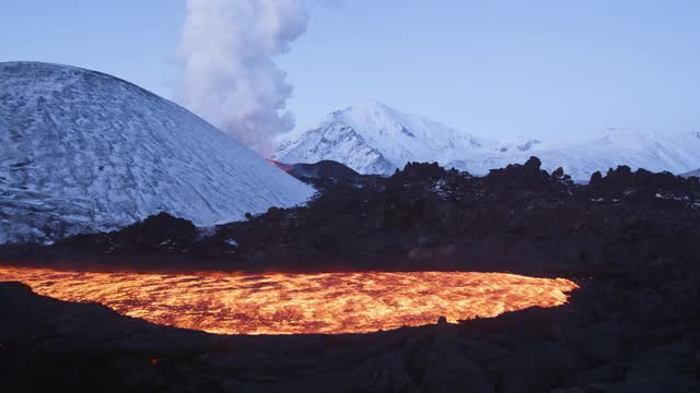 River of lava with erupting volcano in background