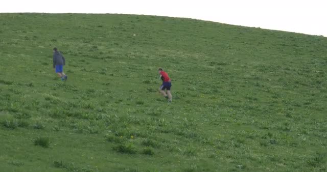 Boys Play Football on the Green Hill