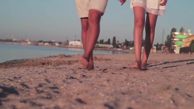 Couple on the beach . The guy and the girl walking barefoot at dawn.