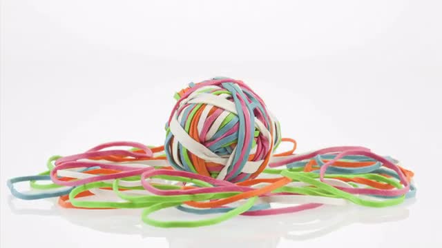 Ball of rubber bands forming pile on white background