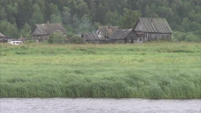 Medium shot of farm building amongst reeds on edge of lake