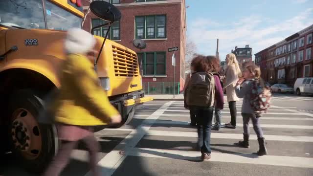 Teacher and pupils getting off school bus and crossing road