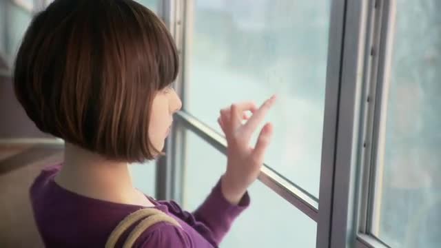 Girl breathing on bus window and drawing in condensation