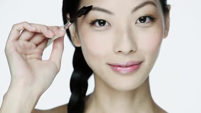 Young woman using eyebrow comb