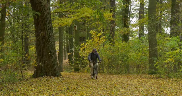 Man in Warm Ushanka Hat With Fur Ear Flaps Tourist in Jacket is Riding the Bicycle Toward Camera by 