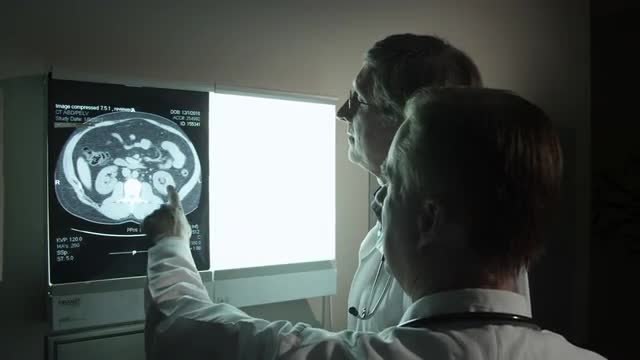 Doctors referencing a patient's midsection x-ray.