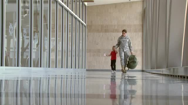 African American soldier and son walking in airport