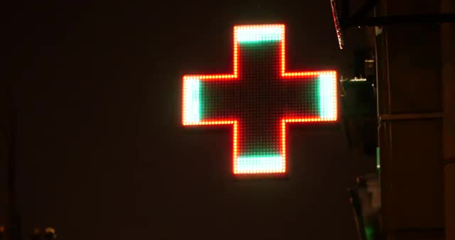 illuminated pharmacy or hospital sign at night with rain