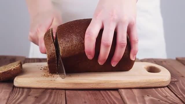 Cook Cut Black Bread on the Board. the Kitchen in the Restaurant. Slow Motion.