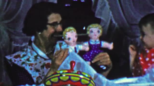 1957: Mom shows cautious baby creepy sibling twin toy dolls. 