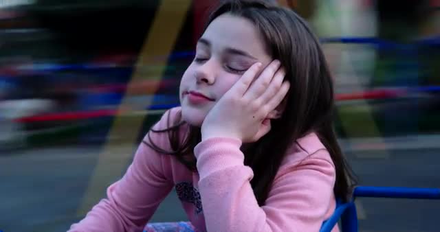Boring Girl Spinning on a Merry-Go-Round in Park