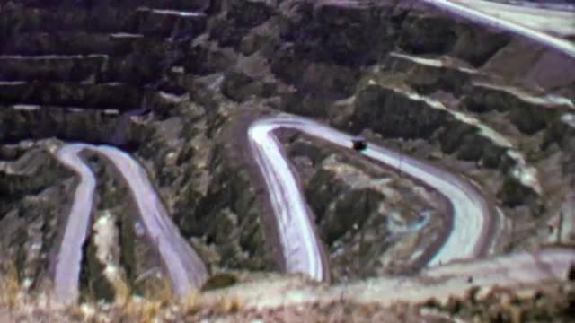 1957: Industrial mining truck drives up windy switchback road.
