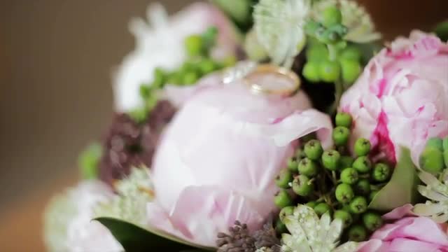Wedding Rings Lie on a Bouquet of Peonies