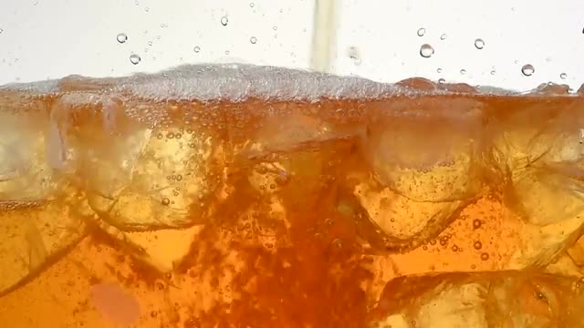 Pouring iced tea in a glass with ice