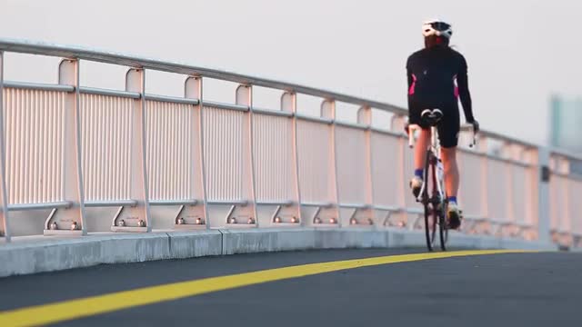 Young Japanese woman cycling on a street by the sea