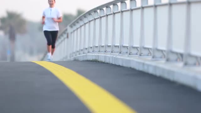 Young Japanese woman jogging on a street by the sea