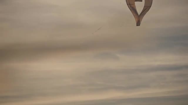 People Fly Heart-Shaped Kite Sky on Background Silhouettes Are Walking Along Seaside International K