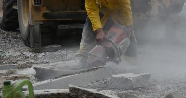 Man Worker in Yellow Workwear Close up is Grinding the Blocks of Concrete by Grinding Machine Flying