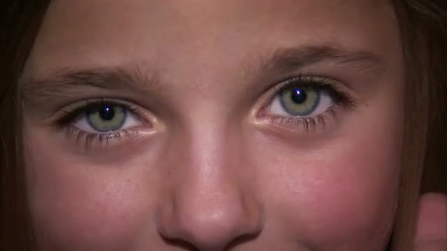 Close up of a young girl playing peek-a-boo.