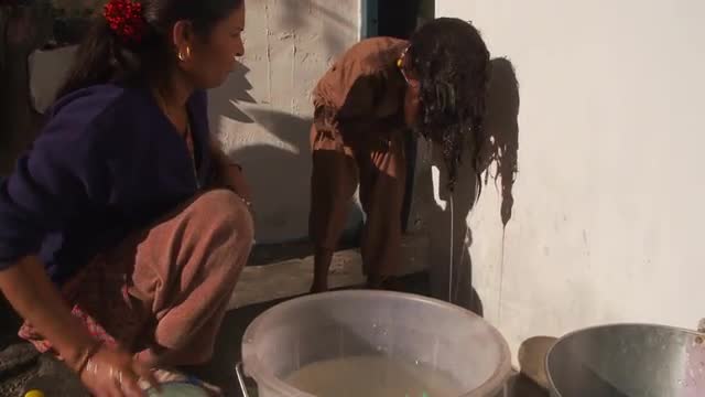 Women rinses little girls hair with water