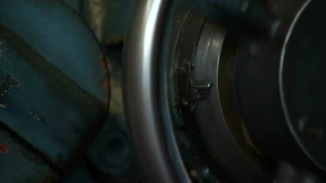 Close up of a metal wheel being turned by hands.