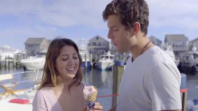 Attractive Couple On Vacation, They Flirt, And Share Ice Cream Cone On Dock 
