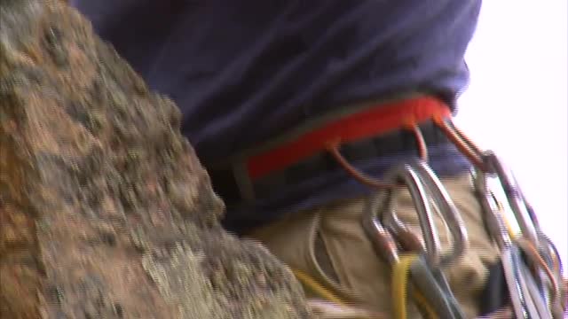 Mountain climber reaching the top of a cliff.