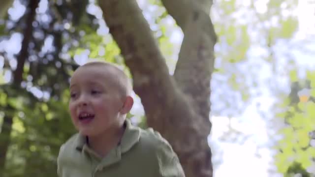 Little Boy Climbs Up Pile Of Bark Chips, Jumps Up And Down, Arms In Air, Proud Of Himself