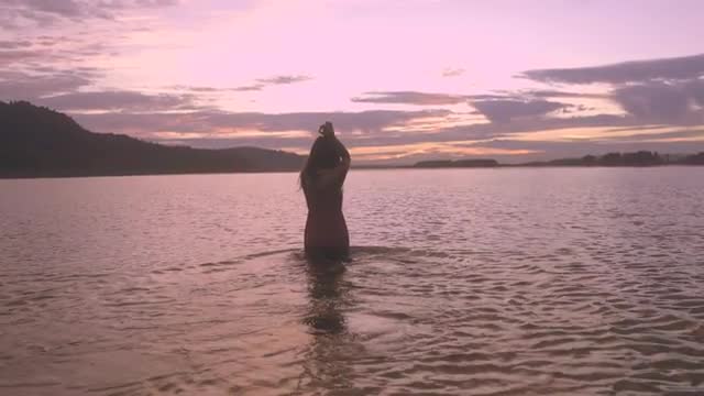 Young Woman Wades Out Into Water, Arms Spread, With Joy (Slow Motion)