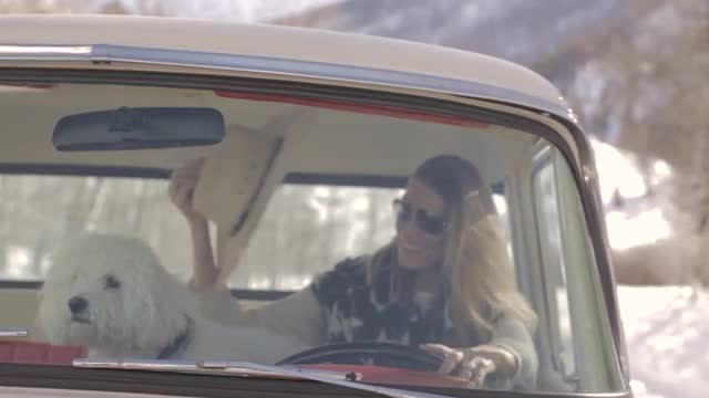 Woman in old vintage truck with her puppy and cowboy hat in winter