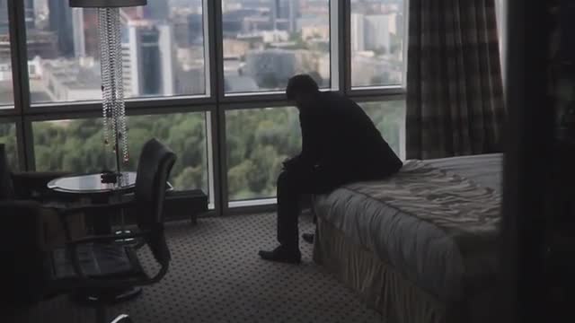 Man In Elegant Suit Sitting On A Bed