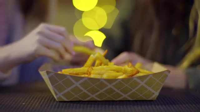 Closeup Of Teen Girls Grabbing Fries From Large Basket