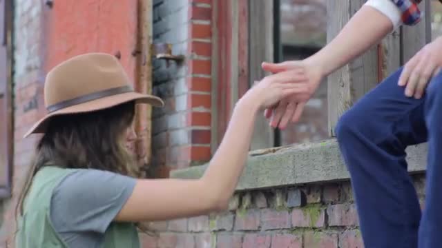 Adventurous Couple Explore City Together, Man Jumps Up And Sits In A Window Of An Old Building, Help
