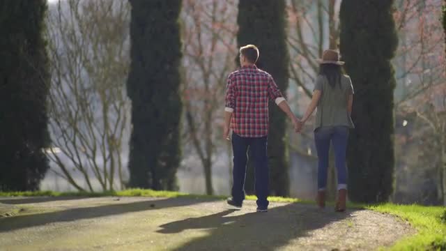 Playful Couple Hold Hands And Enjoy A Walk In The Park