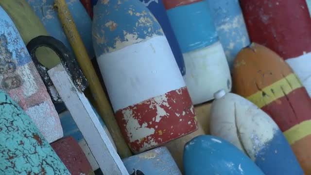 Close-up pan of striped fishing buoys stacked in Massachusetts.