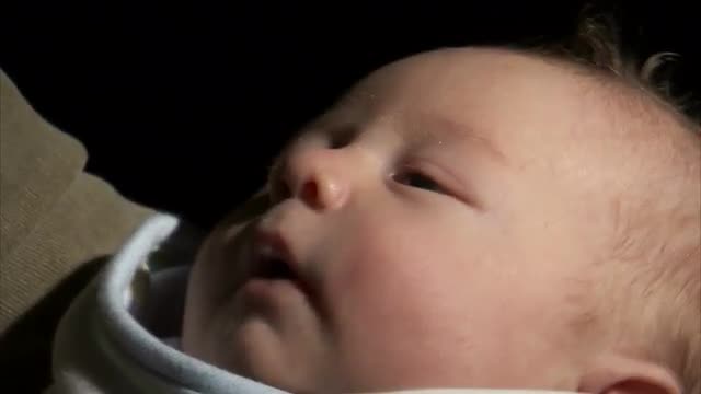 Baby being held in arms.