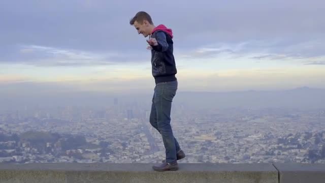 Adventurous Man Spreads His Arms And Balances On A Wall At A Scenic Overlook In San Francisco 