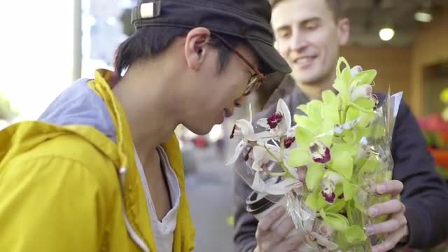 Gay Couple Stop To Smell Flowers Outside Of Flower Shop In San Francisco