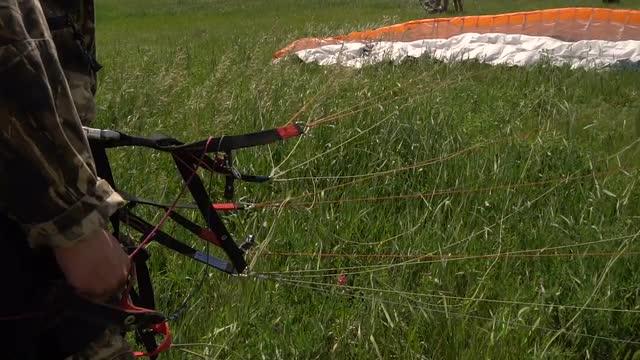 Paragliding in Slow Motion. Hands Athlete Before the Start of a Paraglider Wing on the Ground.