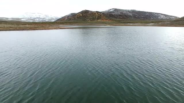Flying over fly fisherman as he is casting is line into a lake