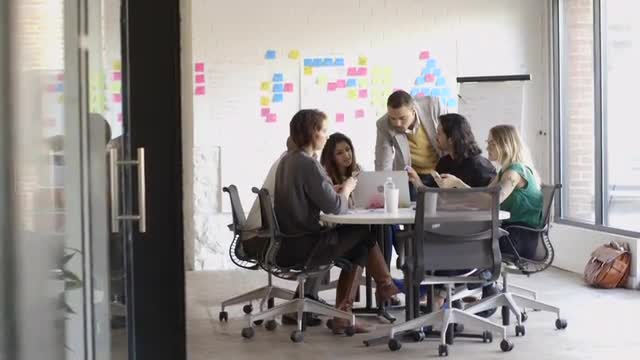 Creative millennial business people using laptop in meeting
