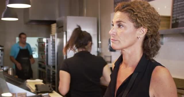 Waitress talking to customer at counter in pizzeria