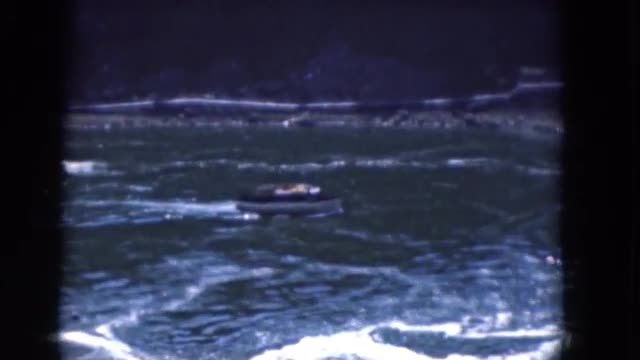 1964: a small boat traveling down a vast rushing river with a large waterfall ALBANY, NEW YORK