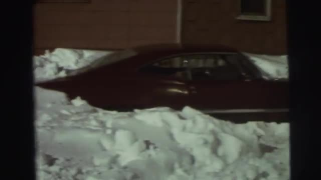 1974: a young boy plays in the snow using a snow shovel. LYNBROOK, NEW YORK