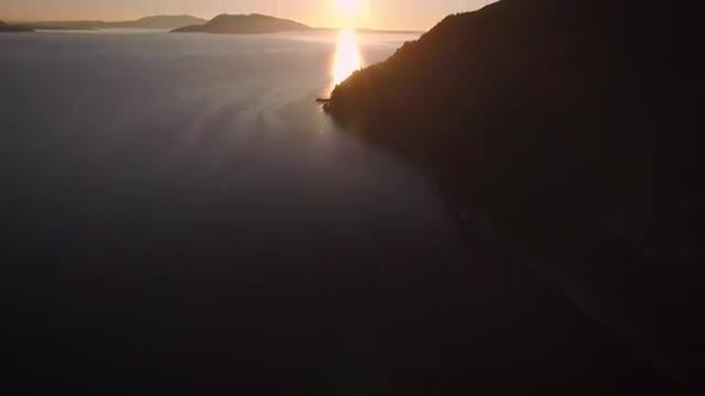 Helicopter Angle Panning Up to Sunset on Ocean Islands with Sun Flares