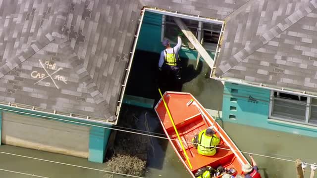 MS POV AERIAL TS ZO ZI Rescue workers patrolling on rescue boats in flooded area and checking homes 